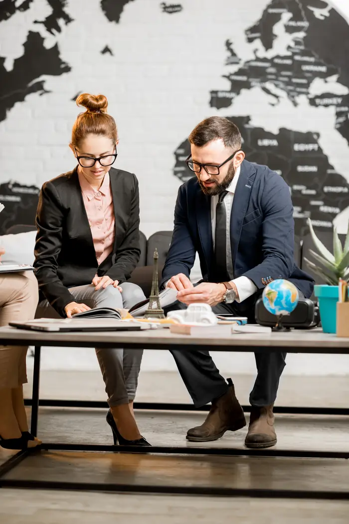 portrait young businesscouple sitting travel agency office with beautiful world map background - Uprise Digital