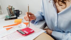 A person calculating costs with a calculator and paperwork at a desk