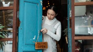 Small business owner turning the open sign on the shop door