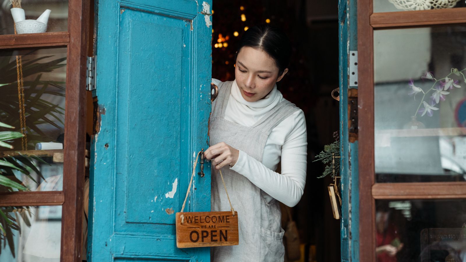 Small business owner turning the open sign on the shop door