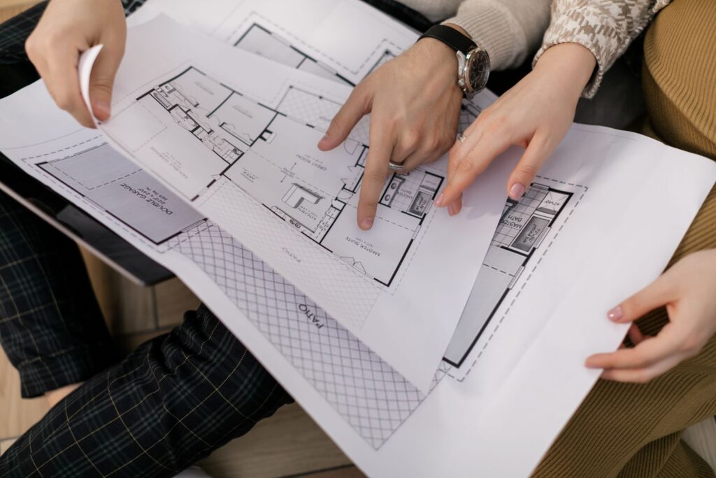 Two people reviewing house floor plans together, the kind of work a construction marketing agency helps sell
