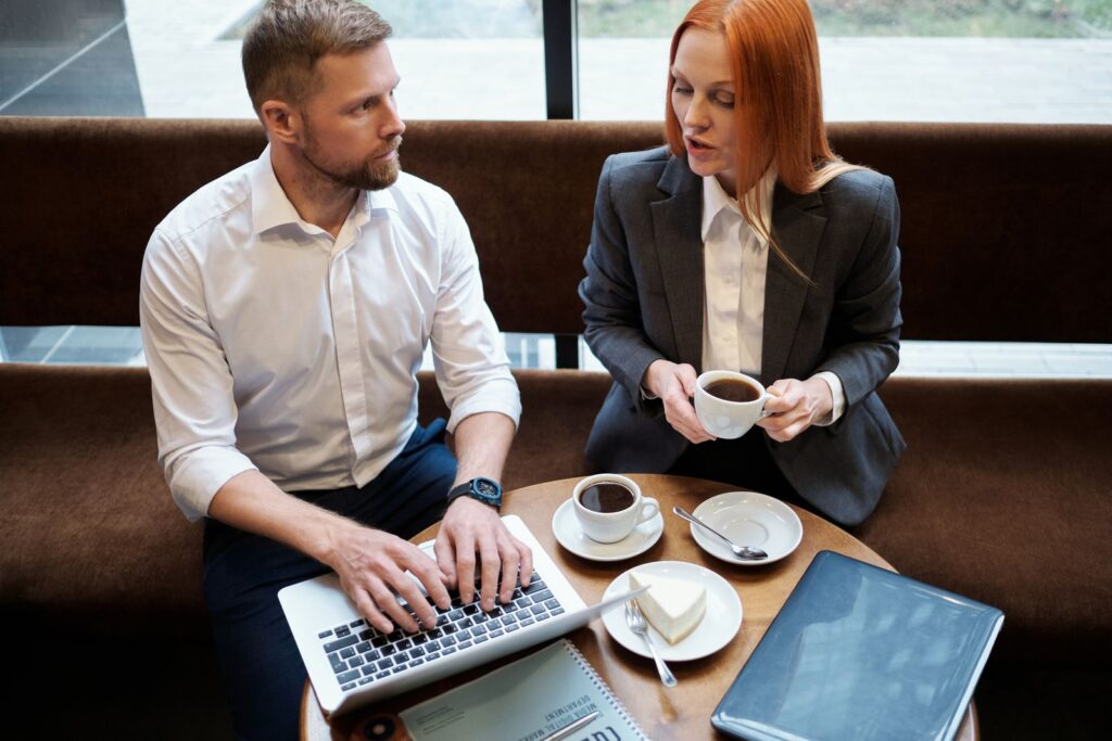 Business owner and consultant discussing an SEO proposal over coffee with a laptop