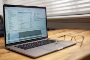 Laptop on a wooden desk showing a website analytics dashboard next to a pair of glasses