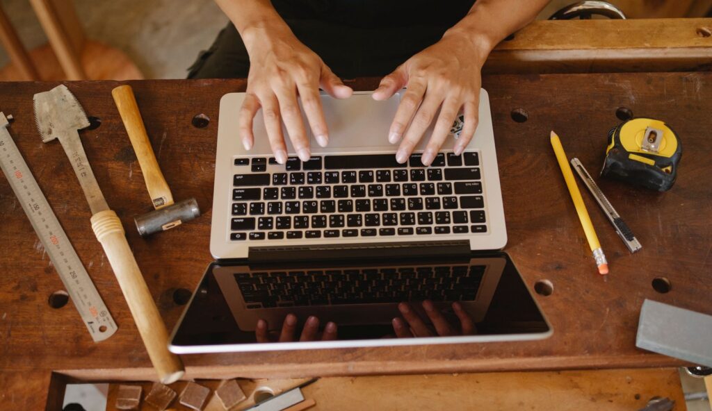 Tradesperson at a workbench typing on a laptop to submit a site to Bing