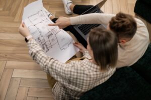 Couple reviewing a house floor plan beside a laptop while planning a new home build
