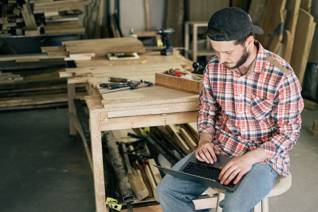 Tradesman in a workshop checking search results and ads on his laptop