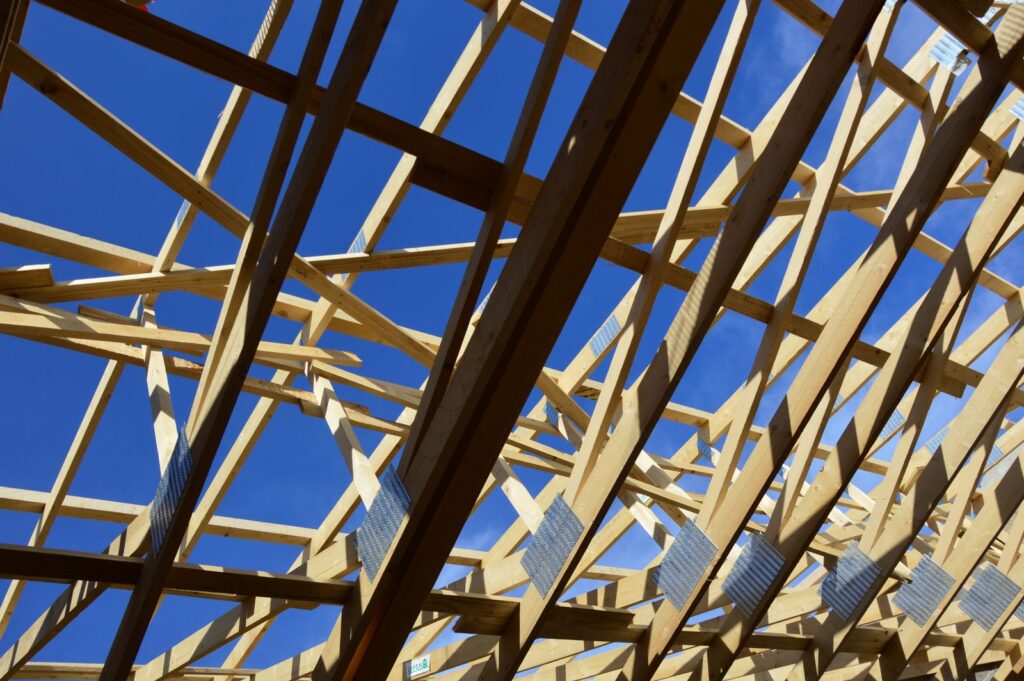 Timber roof trusses on a new house under construction against a clear blue sky