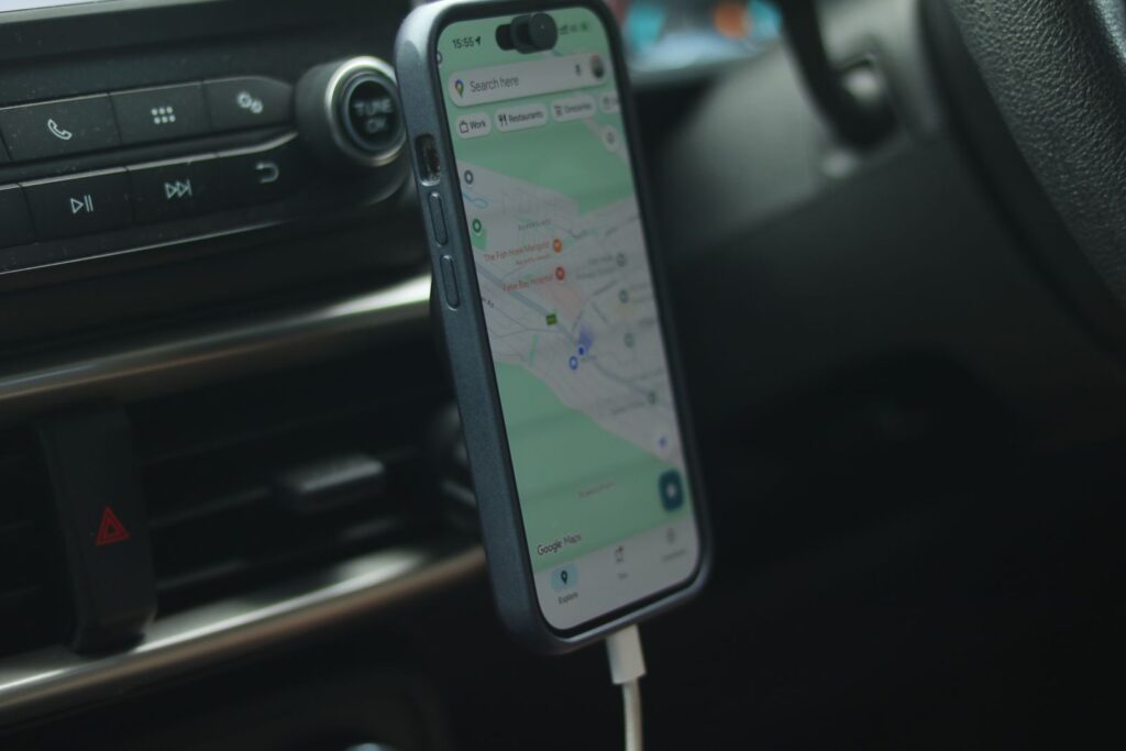 Phone showing a map in a car, as a customer searches Google Maps for a nearby business while on the road