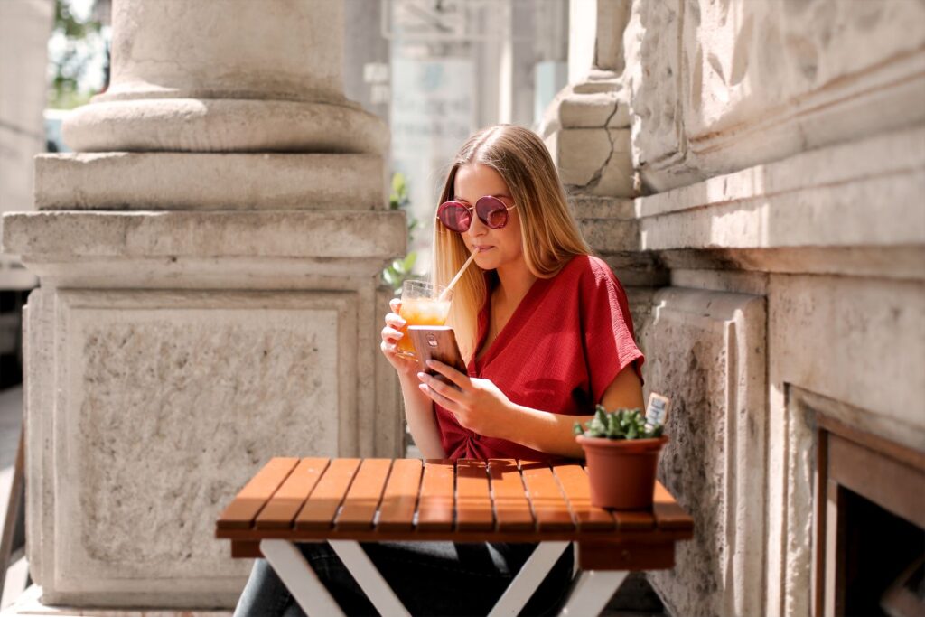 Woman at an outdoor cafe table checking a business on her phone before she calls
