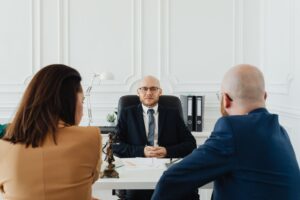 Lawyer meeting two clients across a desk in a bright law office