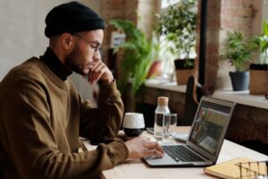 Freelance SEO consultant working on a laptop at a wooden desk in a bright room with plants