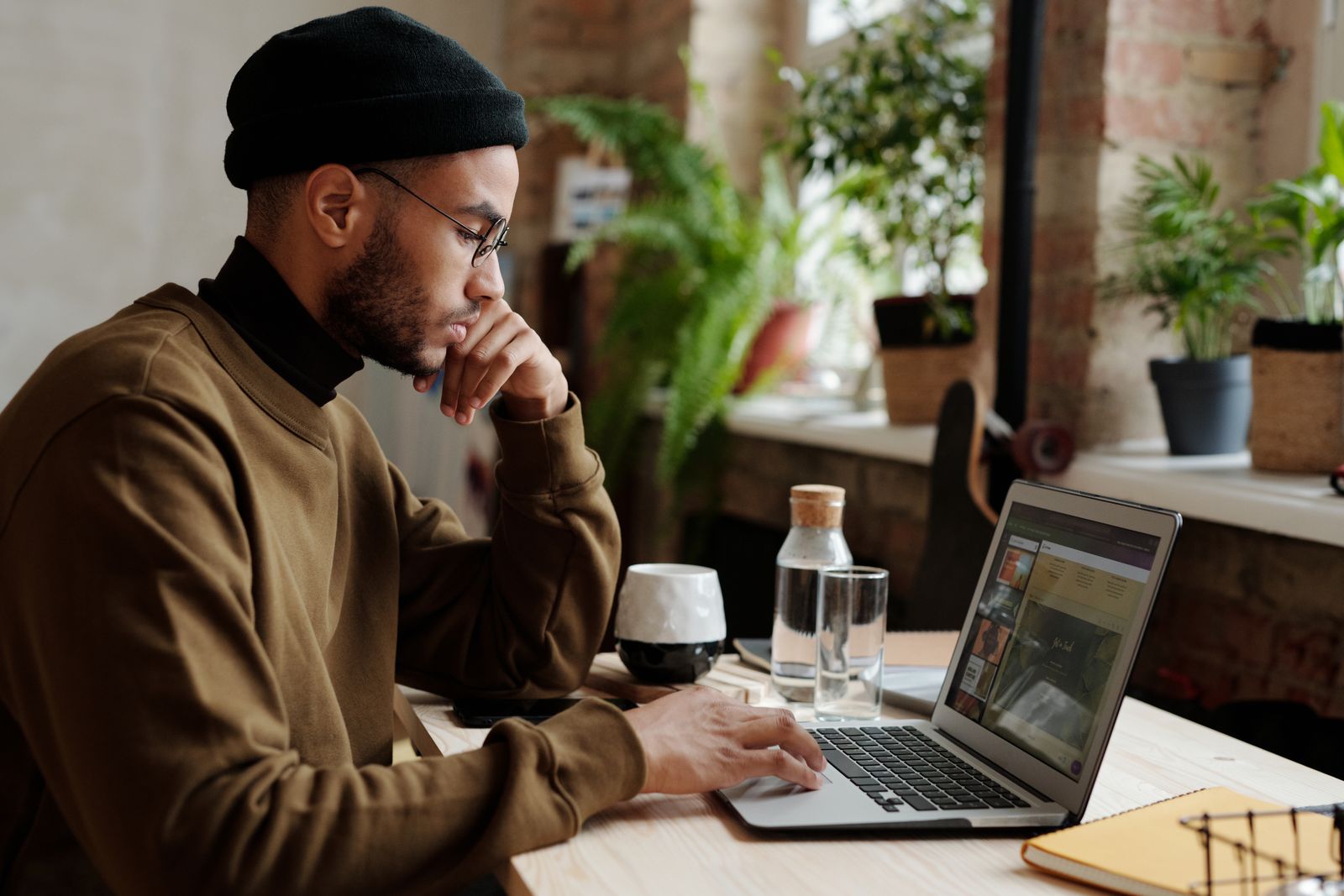 Freelance SEO consultant working on a laptop at a wooden desk in a bright room with plants